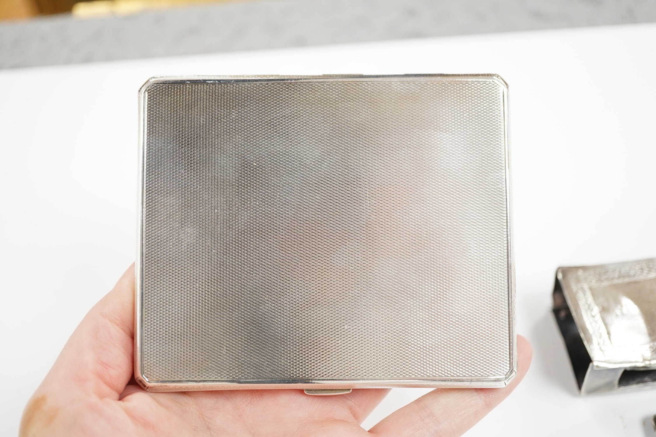 A George V engine turned silver cigarette case, Walker & Hall, London, 1935, 10.2cm and two matchbox holders, one silver.